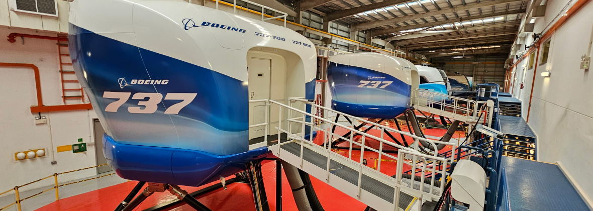 Two Boeing 737 flight simulators inside a training facility.